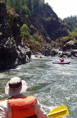 rafter running whitewater in narrow river canyon