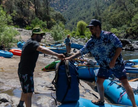 guide unloading drybags at camp on the tuolumne river